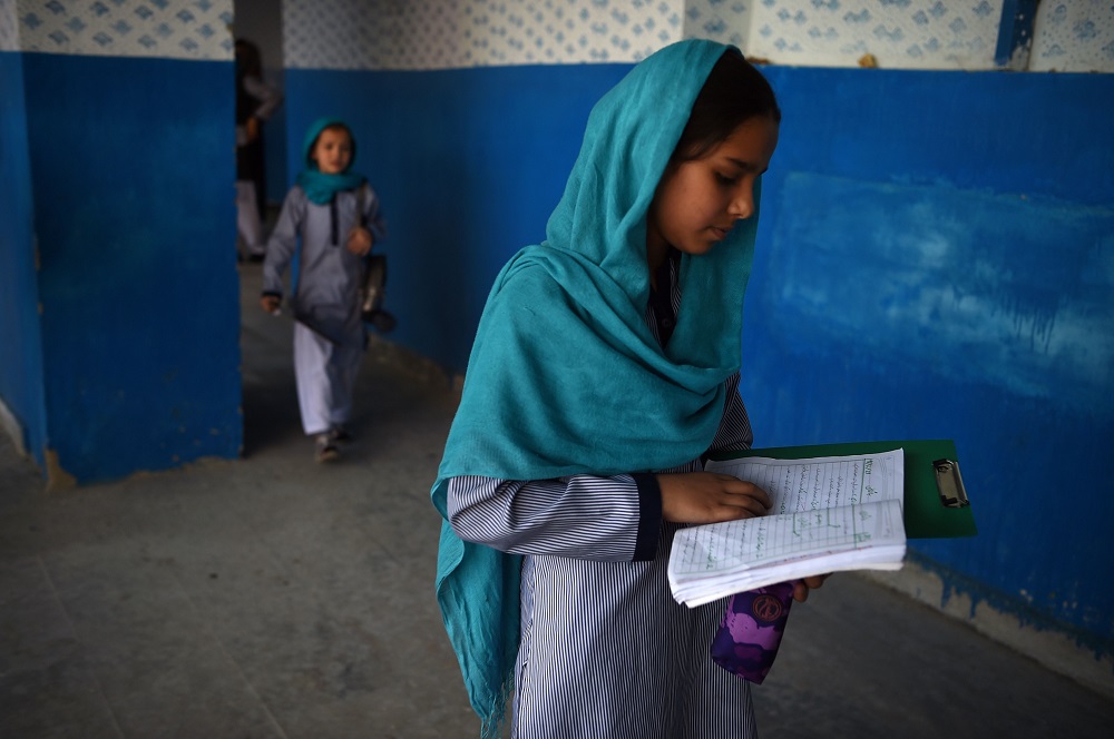 In this photo taken on July 16, 2019, an Afghan schoolgirl check her notebook as she leaves after the mid-term exams at a school in Kabul. u00e2u20acu201d AFP pic          