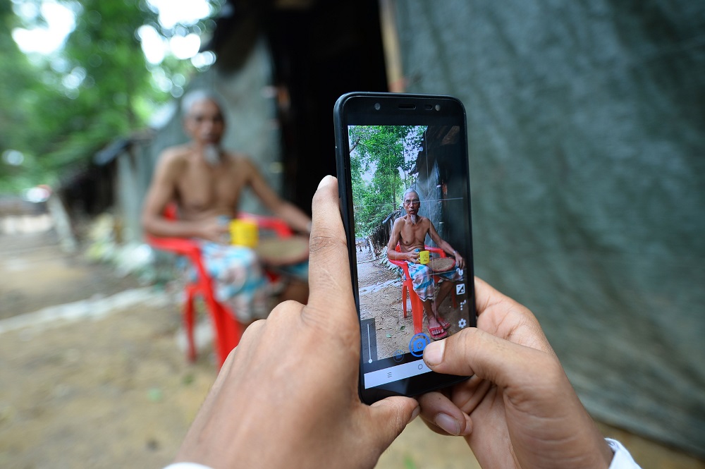 In this picture taken on July 23, 2019, Rohingya youth Mohammad Rafiq uses his mobile phone to take photos of a man by his shack at the Kutupalong refugee camp. u00e2u20acu201d AFP pic 