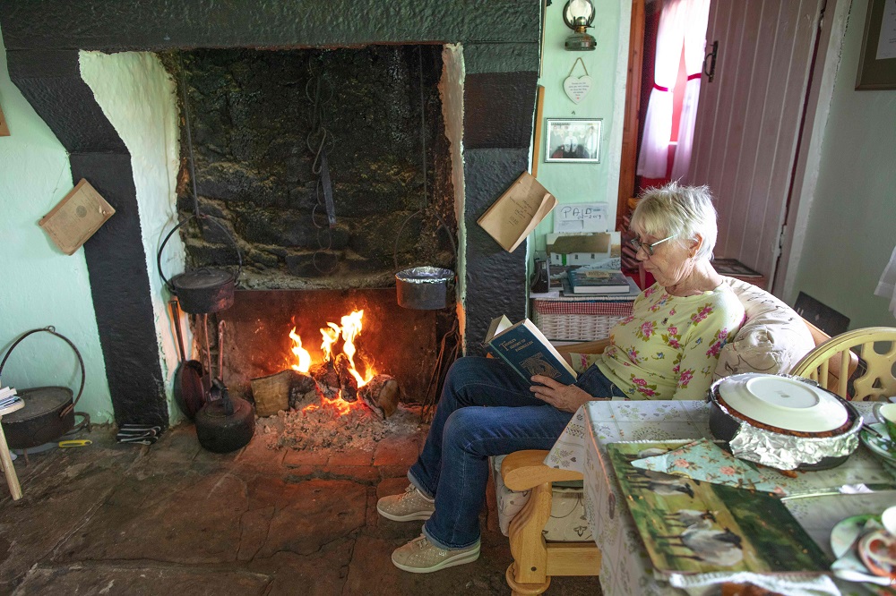 Margaret Gallagher, 77, poses for a photograph next to her open fireplace in her three roomed thatched cottage near the village of Belcoo, Enniskillen, northern Ireland, on the border with the Republic of Ireland, July 15, 2019. — AFP pic 