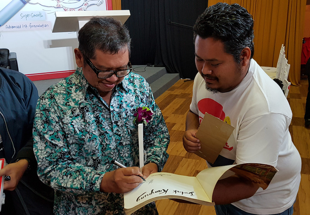 Datuk Mohammad Nor Khalid, or Lat, signs a copy of his book u00e2u20acu02dcKampung Boyu00e2u20acu2122 at the National Art Gallery in Kuala Lumpur August 29, 2019. u00e2u20acu201d Bernama pic