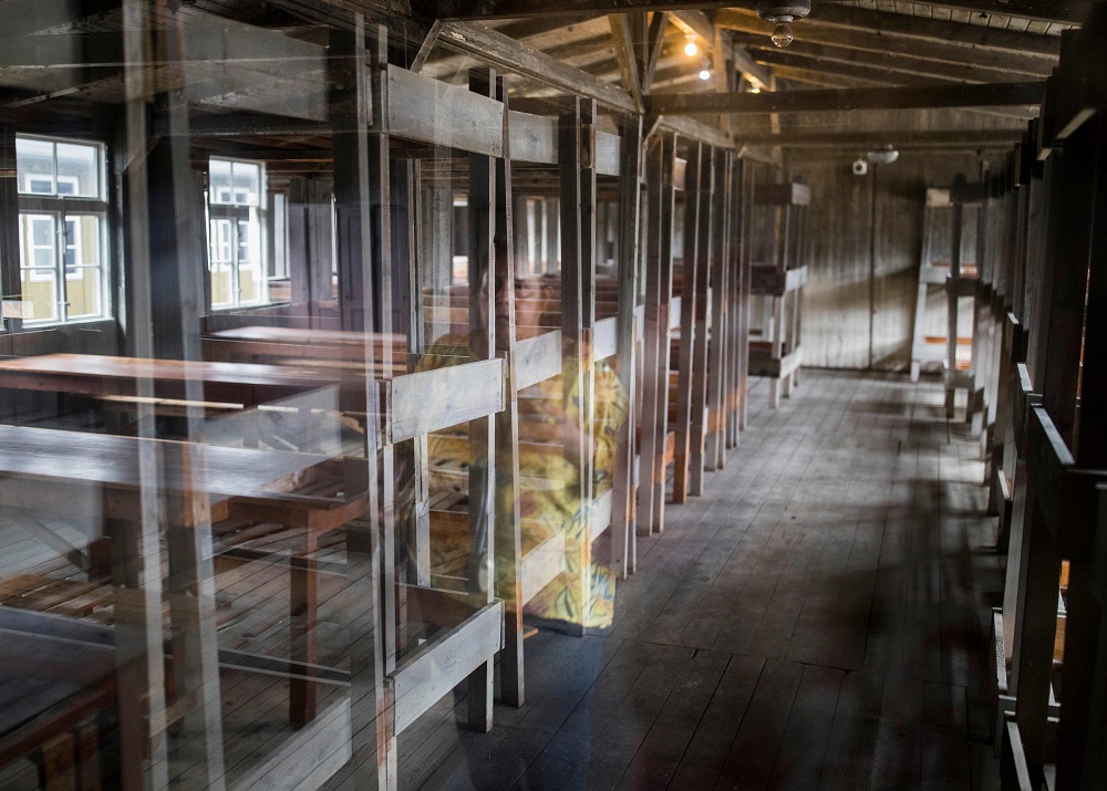 A visitor is reflected in a glass wall as she views the living quarters with bunk beds at the former concentration camp Sachsenhausen in Oranienburg, eastern Germany August 7, 2019. — AFP pic