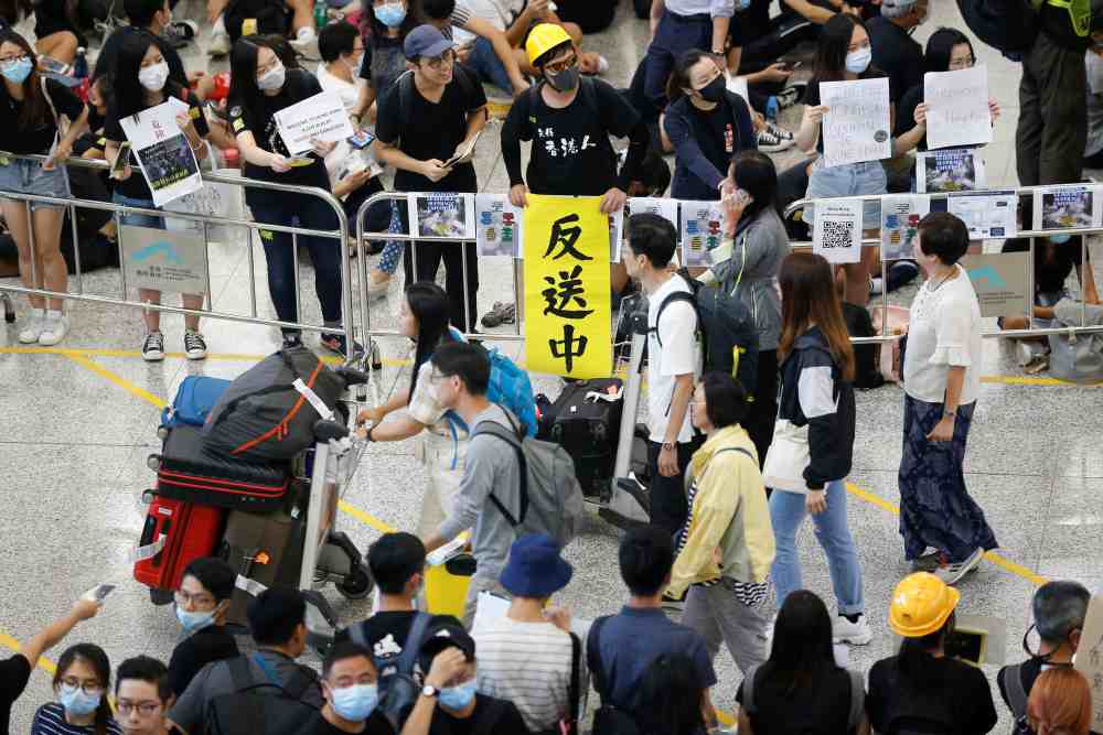 Anti-extradition Bill protesters hold up a sign for arriving travellers during a protest at the arrival hall of the Hong Kong airport, August 9, 2019. u00e2u20acu2022 Reuters pic
