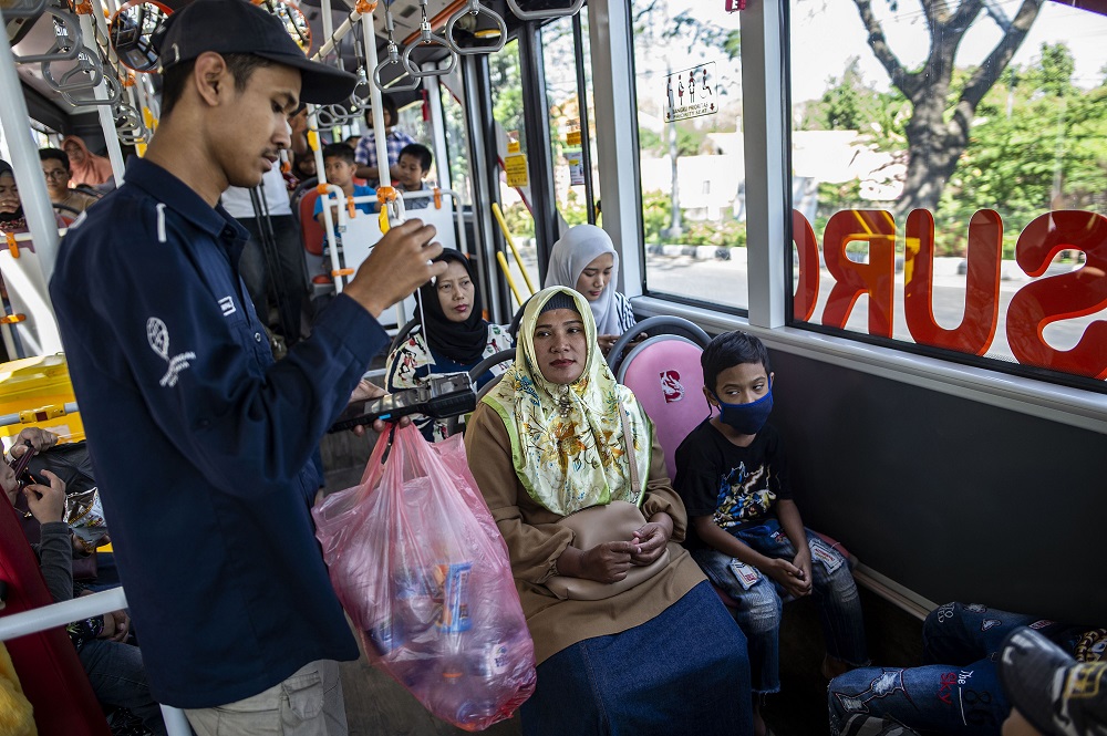 This picture taken on July 21, 2019 shows a bus conductor collecting used plastic bottles as fare payment on board a Suroboyo bus in the Indonesian city of Surabaya. u00e2u20acu201d AFP pic         