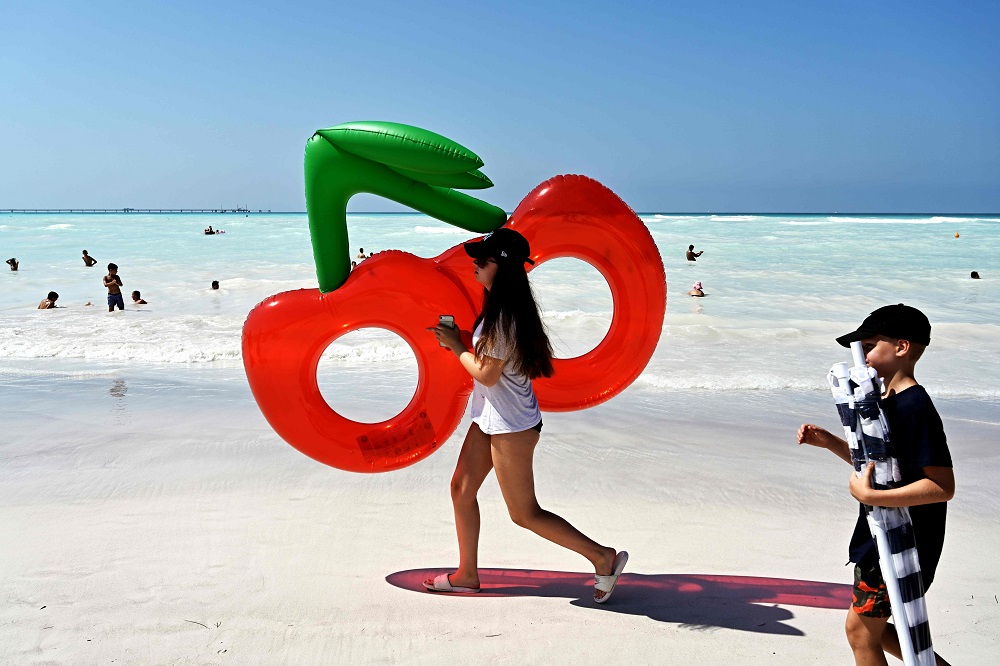 A girl holds a cherry inflatable mattress as she walks on the u00e2u20acu02dcSpiagge Biancheu00e2u20acu2122 (white sand) beach in Rosignano Solvay, a town in Italyu00e2u20acu2122s central Tuscany region July 31, 2019. u00e2u20acu201d AFP pic 