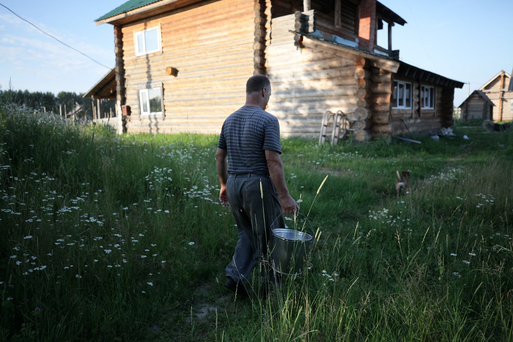 Villager Sergei Benke carries a bucket with milk in the village of Bobrovka, some 350km of Omsk July 31, 2019. — AFP pic