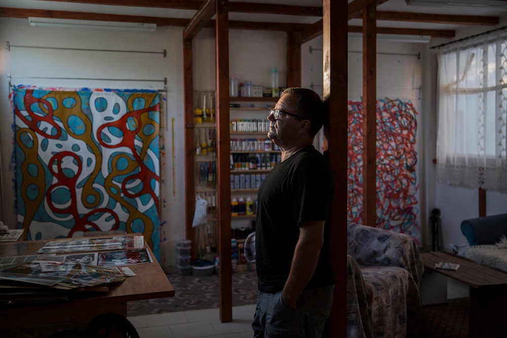 US artist Jeff Ross poses for a photo in his studio next to posters he designed, in Pancevo, near Belgrade August 6, 2019. — AFP pic