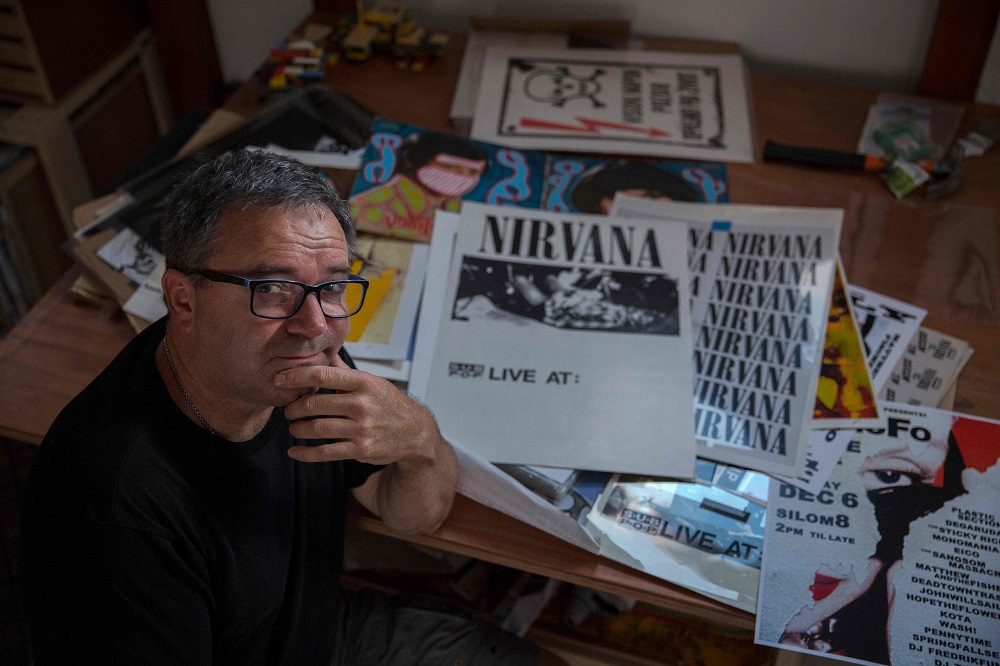 US artist Jeff Ross poses for a photo in his studio next to print posters he designed, in Pancevo, near Belgrade August 6, 2019. u00e2u20acu201d AFP pic         