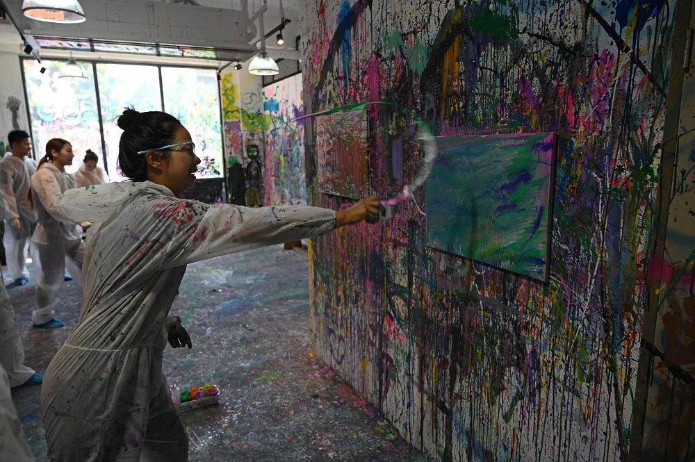 This picture taken on August 1, 2019, shows Huong Kyle creating a watercolour and acrylic painting at Splat Paint House in Singapore. — AFP pic