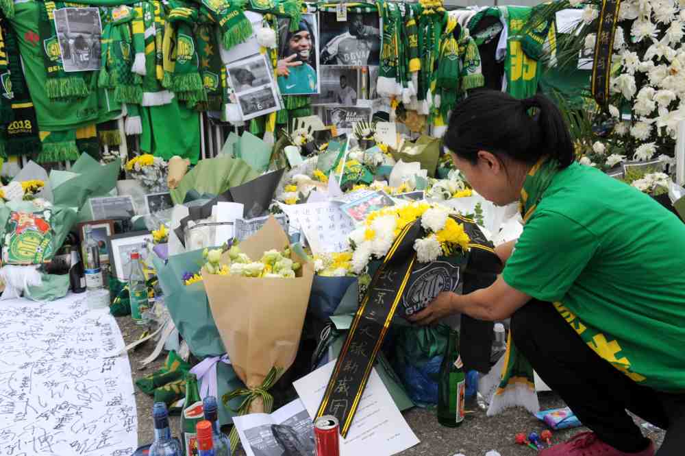 A woman pays tribute to Honduran football player Walter Julian Martinez, who played for Beijing Guoan in Chinese Super League, following the news of his death, outside the club's home field Beijing Workers' Stadium, in Beijing August 14, 2019. u00e2u20acu2022 Handout