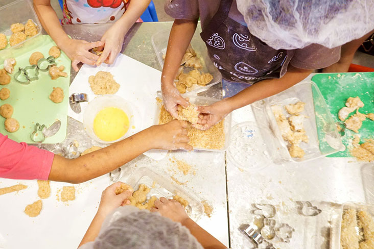 Kids rolling their chicken nuggets in flour during a TedboyCooks class.