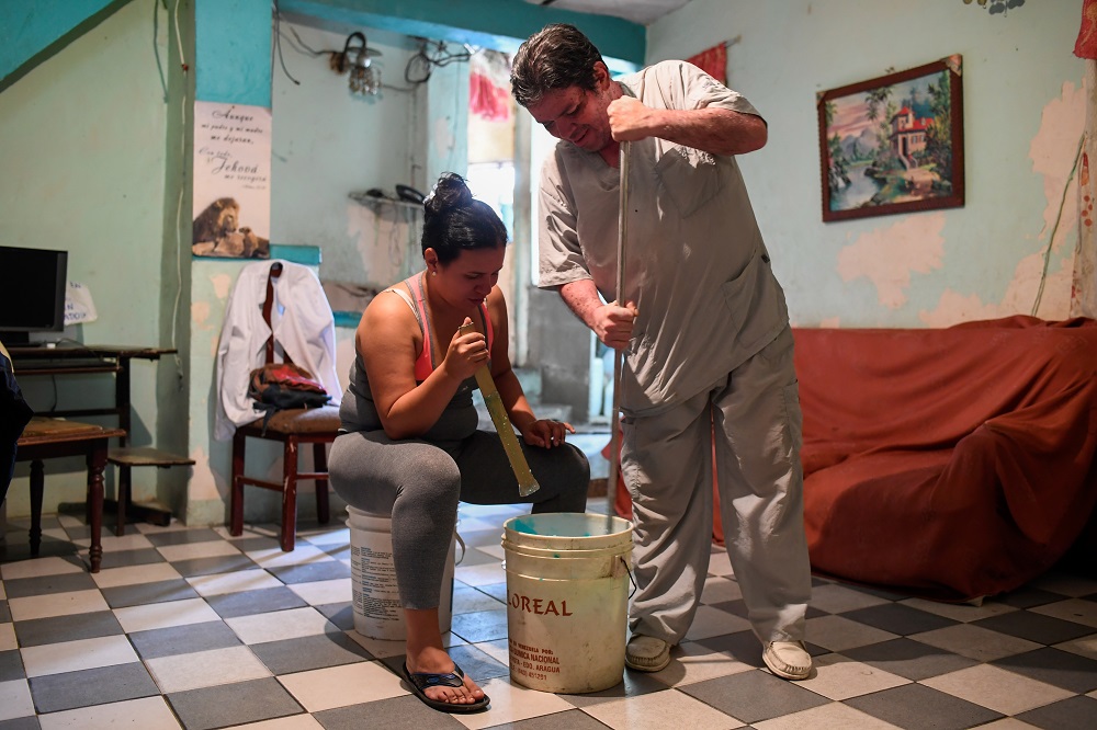 Venezuelan nurse Francis Guillen, who works at a state hospital, and her father make hair gel to sell at her house in Caracas August 24, 2019. — AFP pic