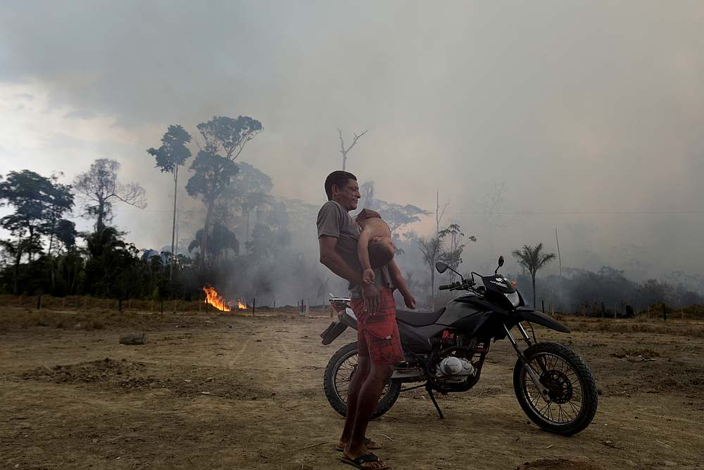 Residents are pictured while a fire burns a tract of Amazon jungle as it is cleared by loggers and farmers near Porto Velho, Brazil August 27, 2019. u00e2u20acu201d Reuters pic