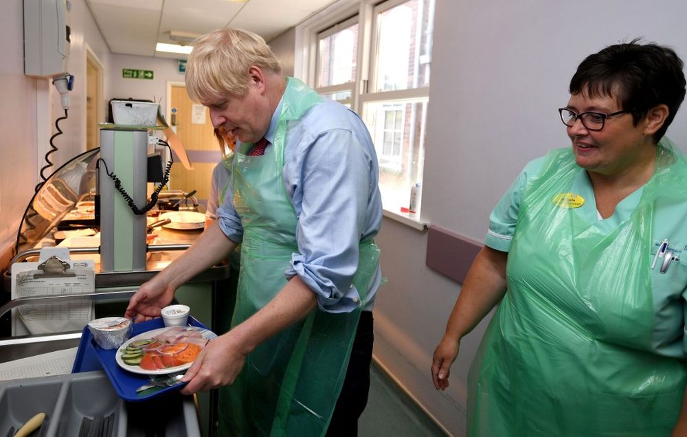 British Prime Minister Boris Johnson (left) prepares to serve food as he visits Torbay Hospital in Torquay, southwest England, August 23, 2019. Johnson makes his debut on the global stage at the G7 summit this weekend. u00e2u20acu201d AFP pic