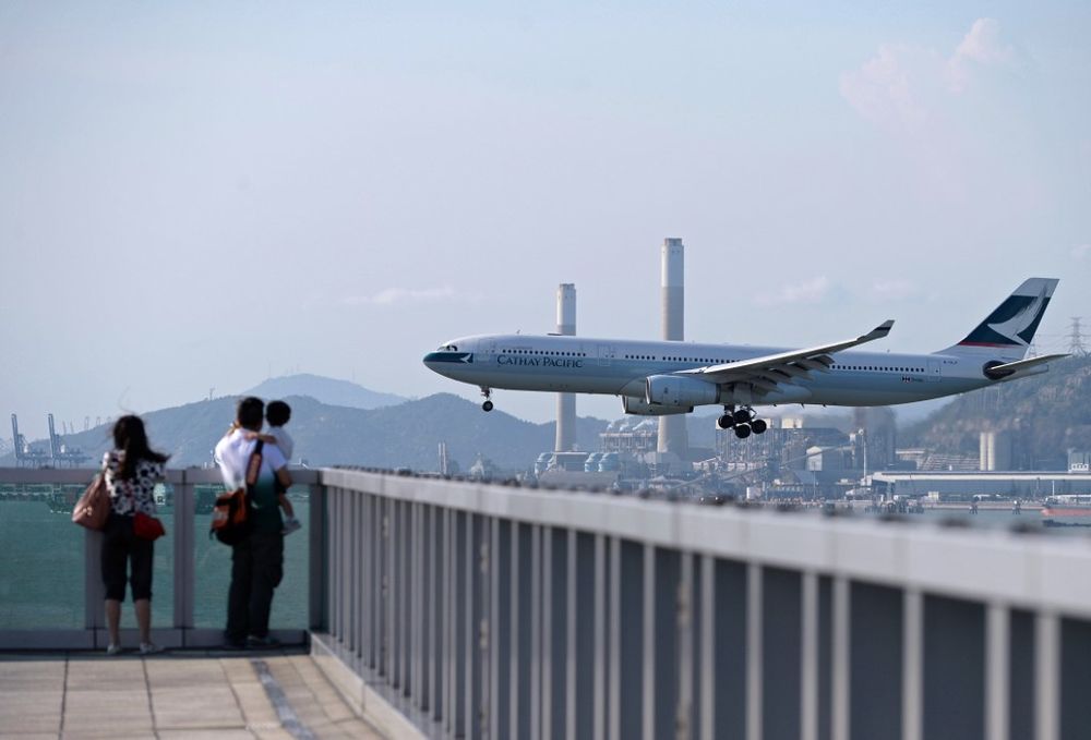 People watch a Cathay Pacific passenger plane landing at Hong Kongu00e2u20acu2122s international airport, August 10, 2014. u00e2u20acu201d AFP pic