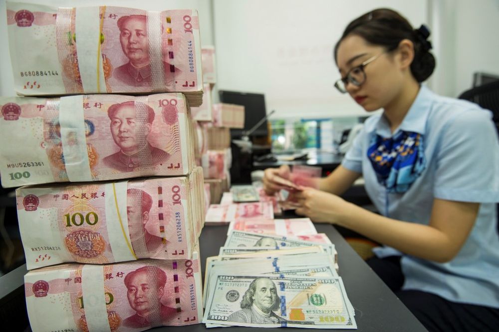 A Chinese bank employee counts 100-yuan notes and US dollar bills at a bank counter in Nantong in Chinau00e2u20acu2122s eastern Jiangsu province on August 28, 2019. u00e2u20acu201d AFP pic