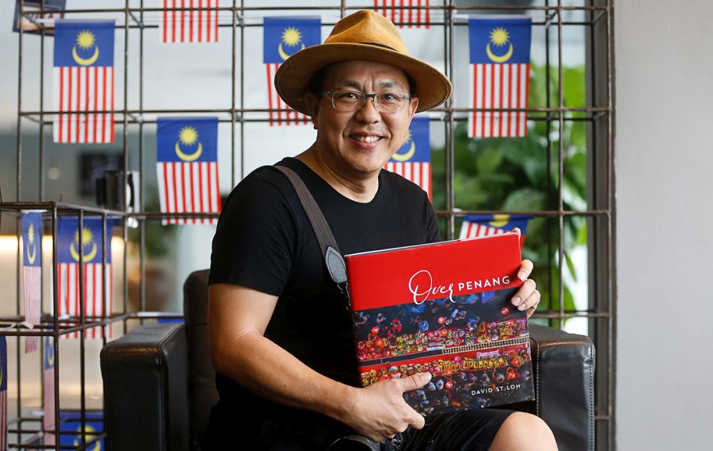 David ST Loh poses with a copy of his book u00e2u20acu02dcOver Penangu00e2u20acu2122 during an interview with Malay Mail in George Town August 6, 2019. u00e2u20acu201d Picture by Sayuti Zainudin