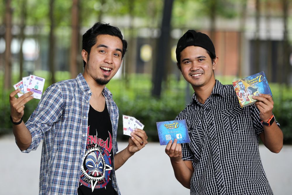 Zamri Mustapha (right) and Haireey Hashnan hold up their board game u00e2u20acu02dcDrama Pukul 7u00e2u20acu2122 during an interview at WePlayGames Cafe in Cyberjaya August 8, 2019.u00e2u20acu201d Picture by Yusof Mat Isa