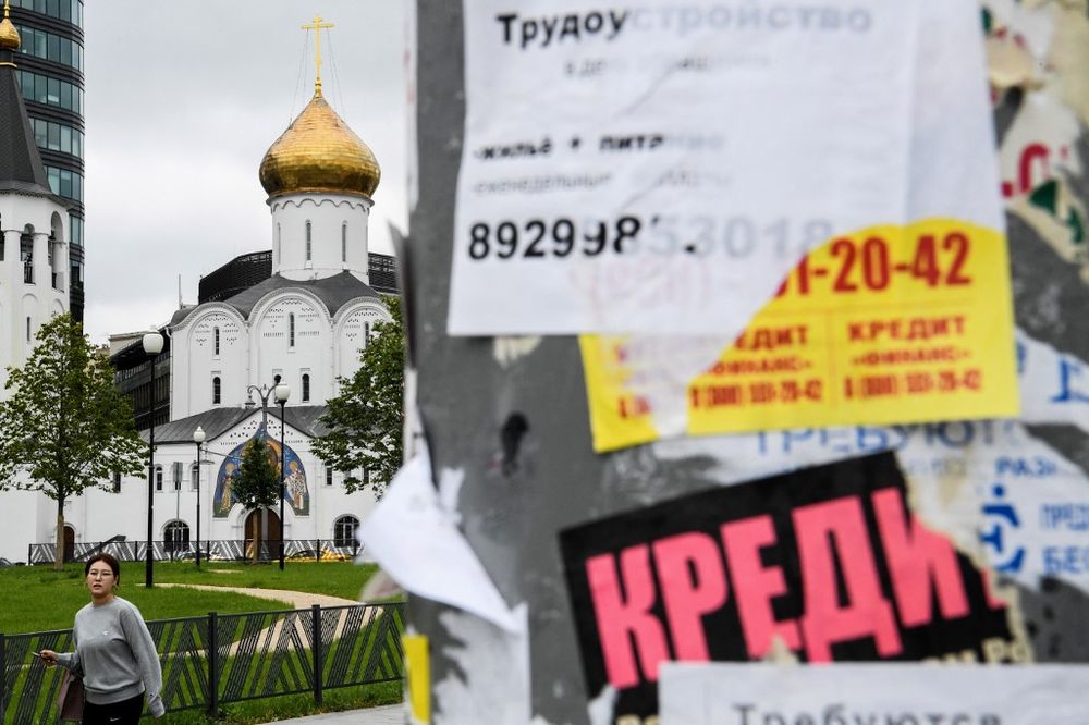 A woman passes a notice advertising loans, with a church seen in the background, in downtown Moscow on August 14, 2019. u00e2u20acu201d AFP pic