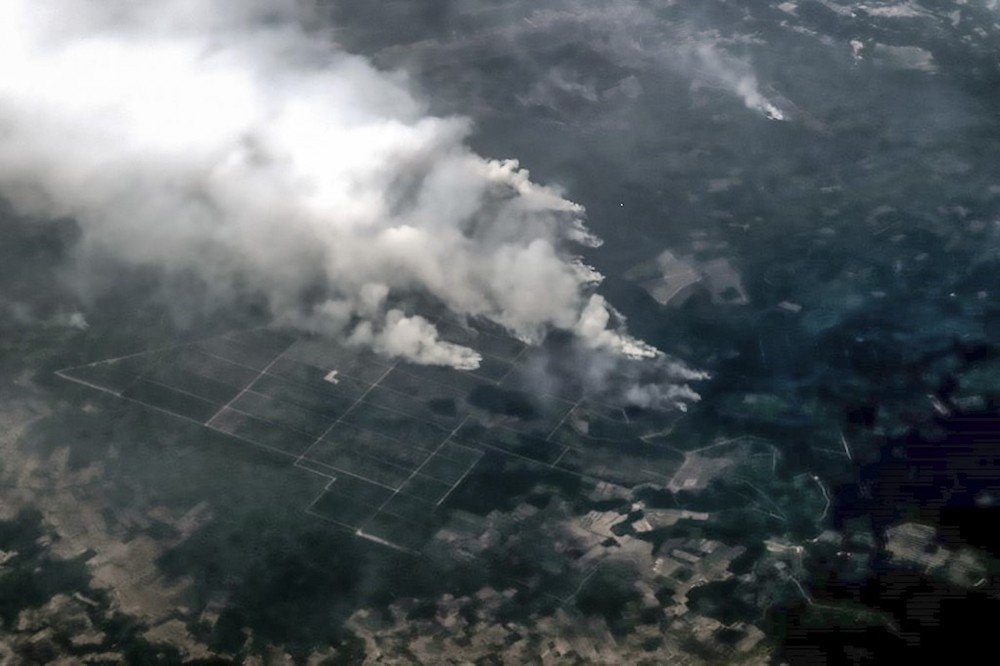 This handout aerial picture taken and released by Indonesia’s accident mitigation agency Badan Nasional Penanggulangan Bencana (BNPB) on September 14, 2019 shows smoke spreading from where the forest fire occurred as seen from above Riau province. — A