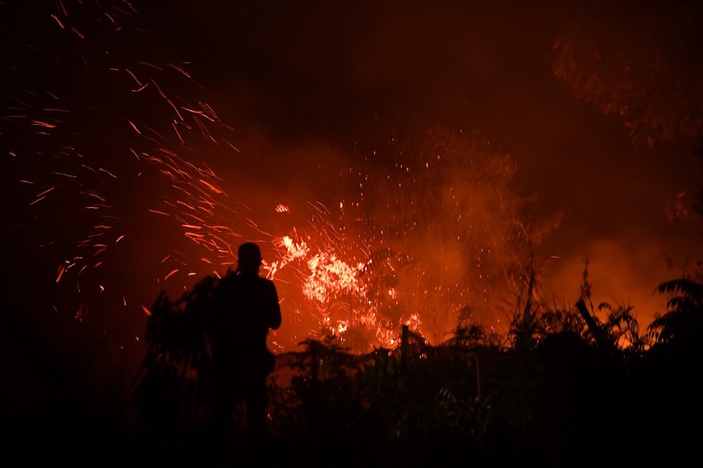 A man stands next to a fire in agricultural land in Kampar, in Sumatra islandu00e2u20acu2122s Riau province on September 16, 2019 as the city is blanketed by smoke from fires. u00e2u20acu201d AFP pic