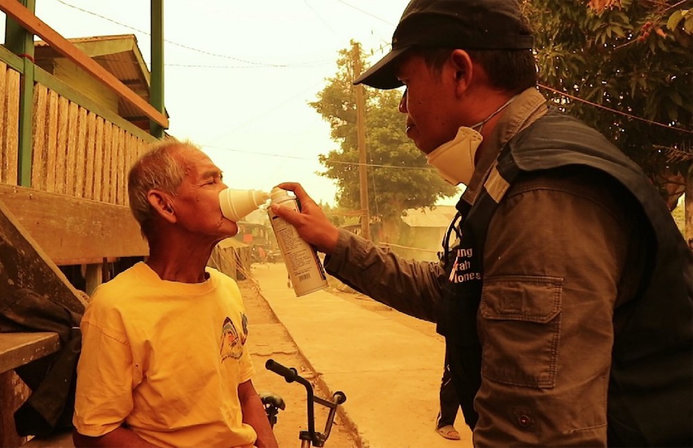 An elder villager gets a dose of oxygen from a Red Cross volunteer outside his home in Jambi September 24, 2019. u00e2u20acu201d AFP pic