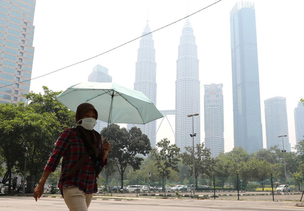 A woman wears a mask as the Petronas Twin Towers are shrouded in haze in Kuala Lumpur September 11, 2019. u00e2u20acu201d Reuters pic