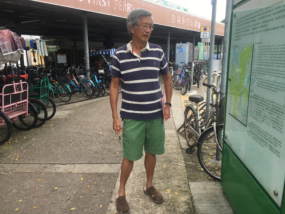 Tom Yam, a resident of Lantau Island, stands in front of a map of the island, whose landscape may be changed with a plan to build artificial islands to ease congestion in Hong Kong August 6, 2019. u00e2u20acu201d Thomson Reuters Foundation pic