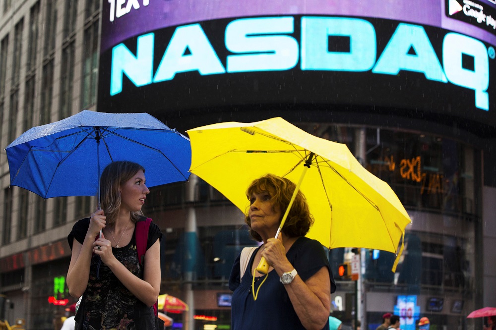 Two women hold umbrellas as they walk past the Nasdaq MarketSite in New Yorku00e2u20acu2122s Times Square August 22, 2013. u00e2u20acu201d Reuters pic