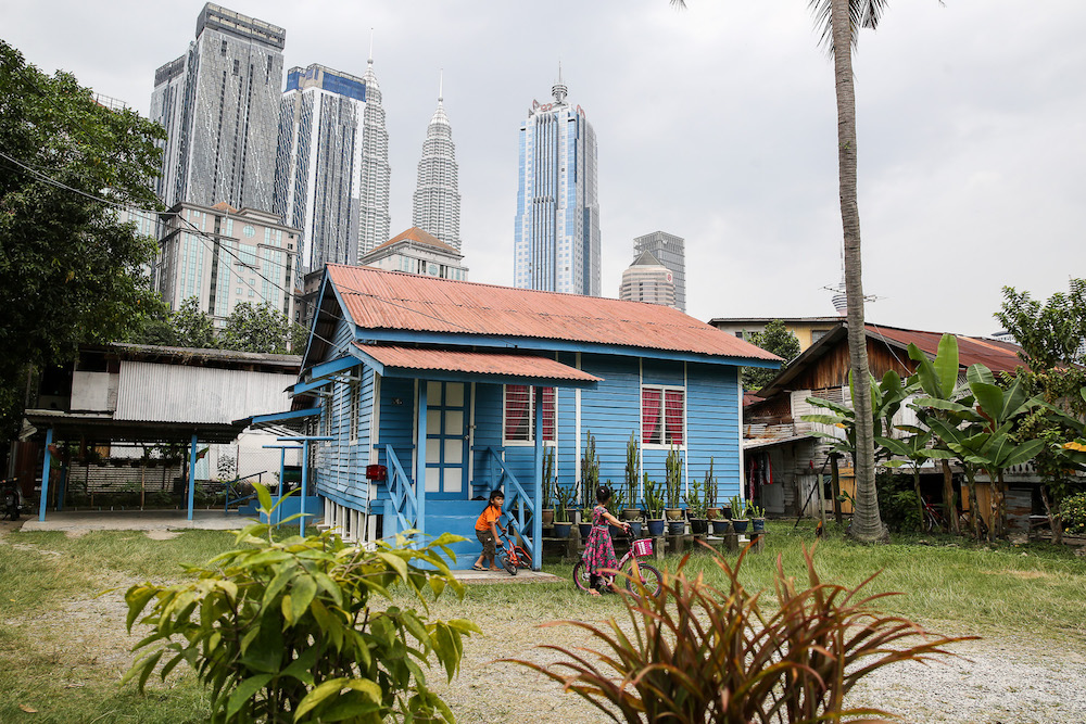 Children playing outside their house in Kampung Baru with the iconic Twin Towers looming behind them. — Picture by Yusof Mat Isa
