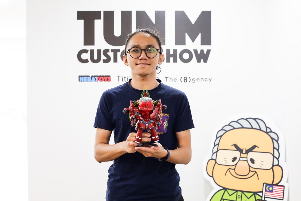 Aleff Ahmad holds up one of his artwork at the ‘Tun M Custom Show’ at the TitikMerah Gallery in Kuala Lumpur.