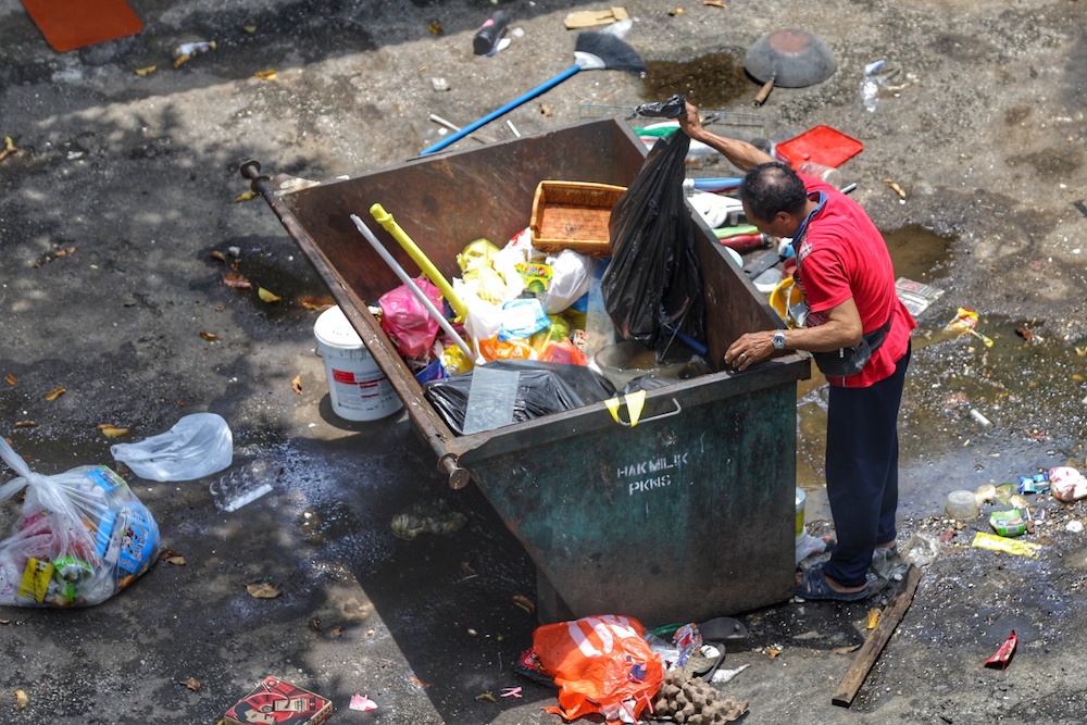 A scavenger rummages through a dumpster in Kuala Lumpur September 29, 2019. — Picture by Ahmad Zamzahuri