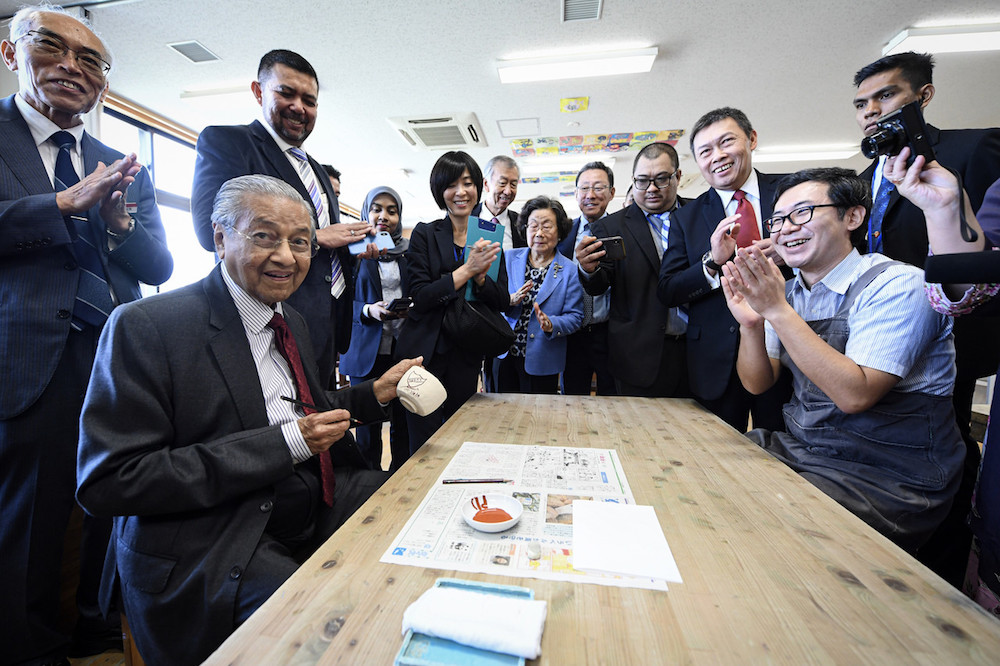 Prime Minister Tun Dr Mahathir Mohamad shows his work of art u00e2u20acu201d a badge with Kedah letterings u00e2u20acu201d during a visit to a ceramic class at Ritsumeikan Elementary School in Kyoto September 7, 2019. u00e2u20acu201d Bernama pic