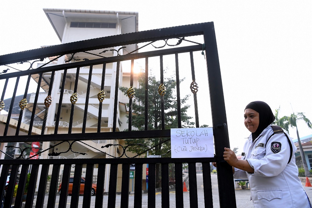 A school security guard is seen putting up a notice in front of a school in Putrajaya September 17, 2019. u00e2u20acu201d Bernama pic