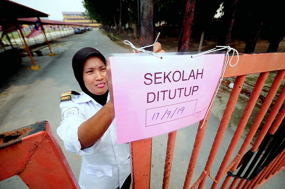 A security guard is seen putting up a notice in front of a school in Klang September 17, 2019. u00e2u20acu201d Bernama pic