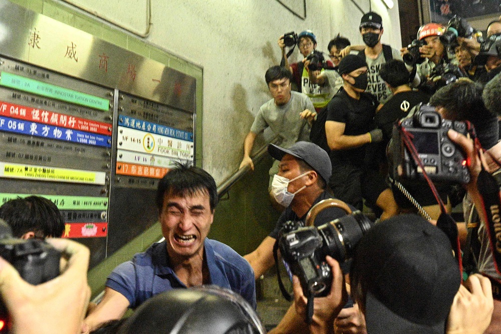 A man (blue shirt) reacts on a stairway as he is attacked, before he was surrounded and beaten on a street outside in North Point in Hong Kong September 15, 2019. — AFP pic