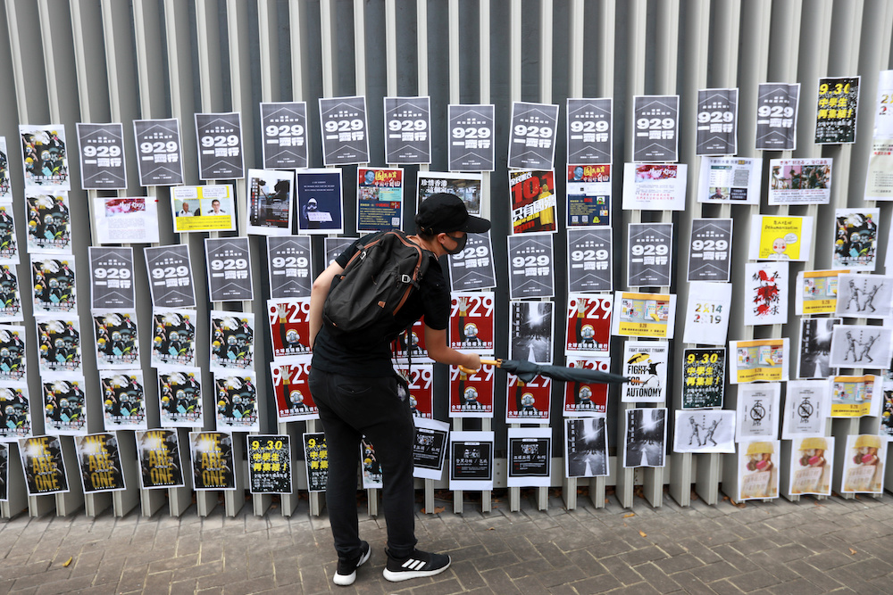 An anti-government protester uses an umbrella to stick a banner on a Lennon Wall at Admiralty district in Hong Kong, China September 28, 2019. u00e2u20acu201d Reuters picnn