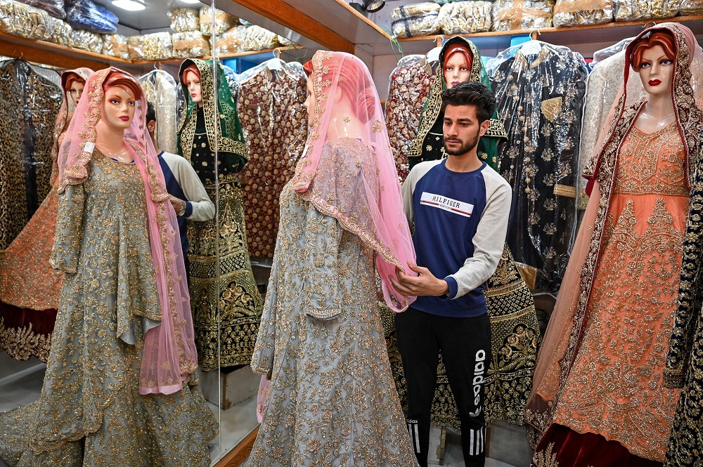 In this file picture taken on June 3, 2019, a Kashmiri shopkeeper displays a wedding dress at a market ahead of the Muslim festival of Eid al-Fitr in Srinagar. u00e2u20acu201d AFP pic          