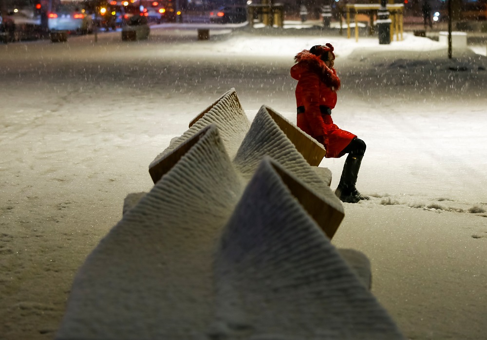 A woman sits on a bench as she poses for a picture during a snowfall in Almaty, Kazakhstan February 6, 2018. u00e2u20acu201d Reuters pic       
