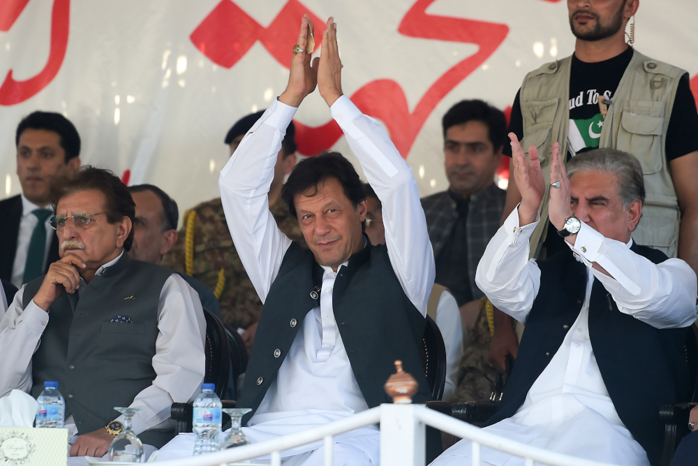 Pakistanu00e2u20acu2122s Prime Minister Imran Khan is accompanied by Foreign Minister Shah Mehmood Qureshi (right) and prime minister of Pakistan-administered Kashmir Raja Farooq Haider (left) as he greets the crowd during a rally in Muzaffarabad September 13, 2019. 