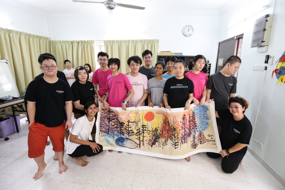 The special needs youths from Gem & Bread, along with the co-founders Sharanya and Tan, hold up an artwork that the youths made. — Picture by Ahmad Zamzahur