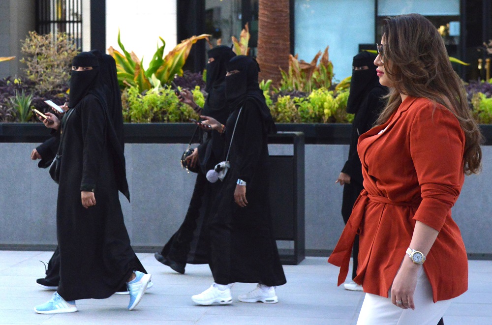 Saudi human resources professional Mashael al-Jaloud, 33, walks in western clothes past women wearing niqab, an Islamic dress-code for women, at a commercial area in the Saudi capital Riyadh on September 3, 2019. u00e2u20acu201d AFP pic       