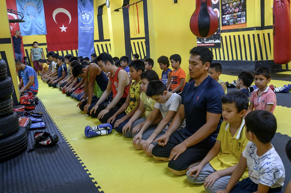 In this photograph taken on August 29, 2019, trainers and children from Muslim Uighur minority pray as they attend a Muay Thai training session in a boxing academy in Istanbul. — AFP pic