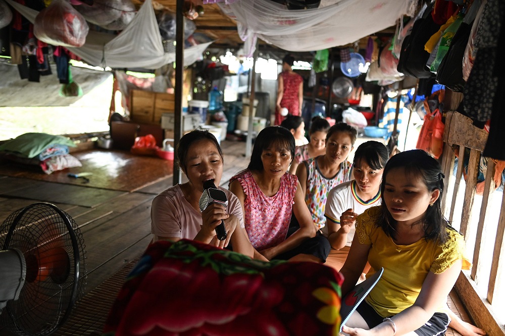 This photograph taken on September 8, 2019 shows Nguyen Thi  Hang (left), a Vietnamese migrant worker living for the past seven years in a floating guesthouse on the banks of the Red River in Hanoi, singing karaoke along with other workers. — AFP pic       