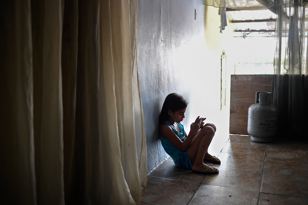 Venezuelan Paola Osorio, 7, whose parents emigrated, uses a cell phone at her house of the San Agustin neighbourhood in Caracas August 5, 2019. u00e2u20acu201d AFP pic       