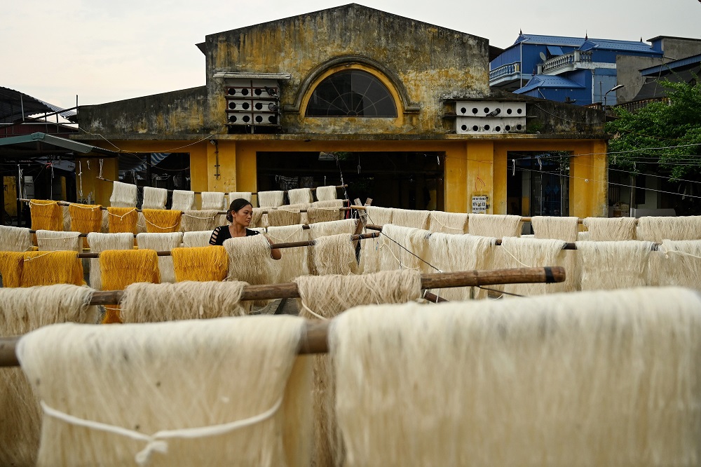 This photograph taken on September 17, 2019 shows a worker drying collected silk thread yarns in an open courtyard in Co Chat village in Vietnam’s Nam Dinh province. — AFP pic