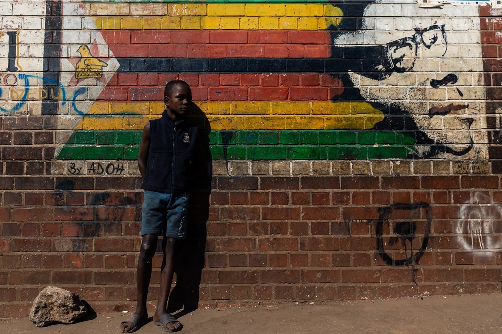 A young boy stands beside a mural of former Zimbabwe President Robert Mugabe in Mbare district of Harare September 6, 2019. u00e2u20acu201d AFP pic