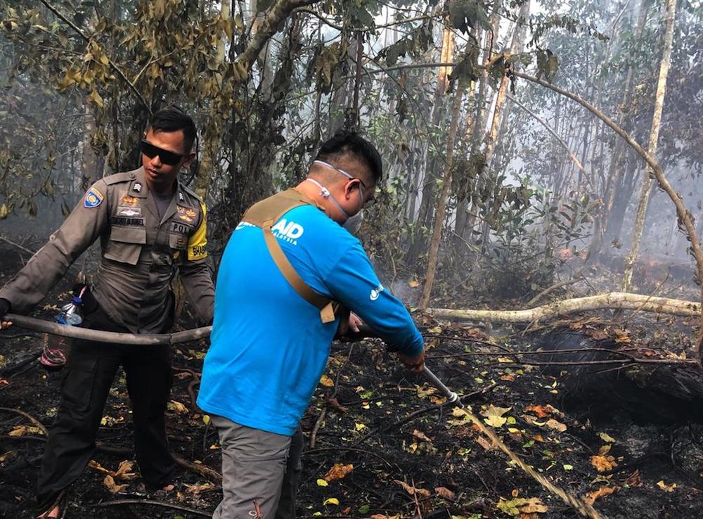 Singaporean Benjamin Tay (in blue) joined volunteer firefighters in Tanjung Sari village to help put out a peatland fire. u00e2u20acu201d TODAY pic