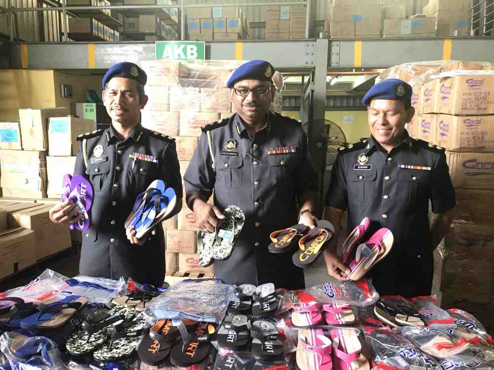 KPDNHEP chief enforcement officer V. Ravichandran (centre) showing the counterfeit sandals, worth more than half a million, seized at a company in Pusing. u00e2u20acu2022 Picture by John Bunyan
