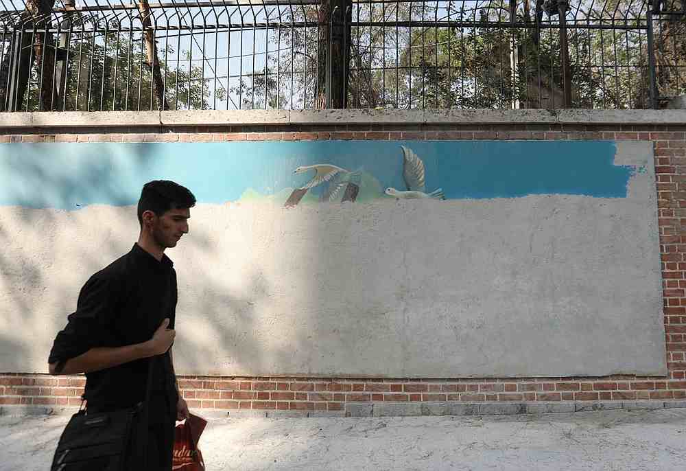 A young Iranian man walks past a mural painting, partially covered with cement, on the wall of the former US embassy in the capital Tehran September 29, 2019. u00e2u20acu201d AFP pic