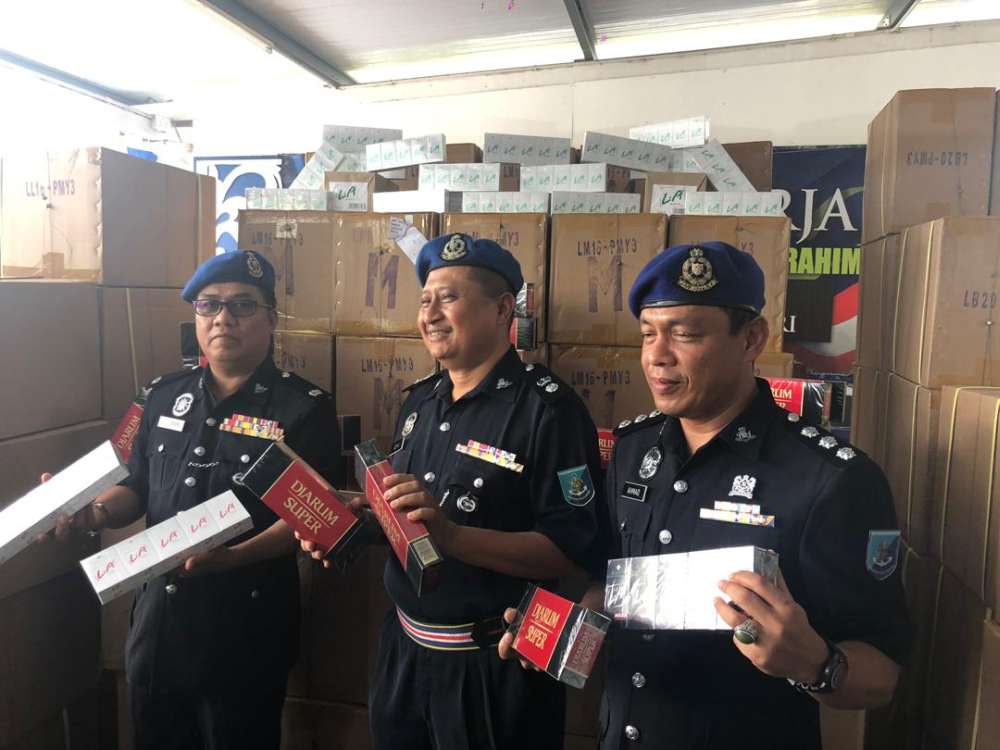 Region Two marine police deputy commander Superintendent Noor Azman Jamal (centre) with the seized contraband cigarettes at the Region Two marine police base in Tampoi, Johor Baru today. u00e2u20acu201d Picture by Ben Tan